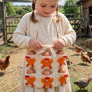 May include: A cream-coloured crochet egg gathering apron featuring six square pockets, each decorated with a bright orange crocheted chicken motif. The apron is tied at the waist with a matching cream-coloured crochet string and holds six brown chicken eggs.