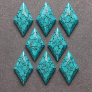 Puede incluir: Ocho gemas turquesas en forma de diamante con un patrón oscuro similar a una telaraña. Las gemas están dispuestas en un patrón de cuadrícula sobre un fondo gris. Las gemas tienen una superficie pulida y lisa.