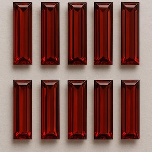 May include: Ten rectangular, faceted, deep red gemstones are arranged in two rows of five. Each gem has a rectangular shape with a slightly tapered top and bottom. The gems are a rich, saturated red colour, and appear to be transparent.