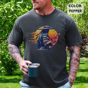 Op de afbeelding: Pepperkleurig t-shirt met een afbeelding van een samoerai-krijger met een zwaard tegen een zonsondergang. Het ontwerp bevat een gele zon en oranje en rode tinten. De tekst "COLOR: PEPPER" staat rechtsboven.