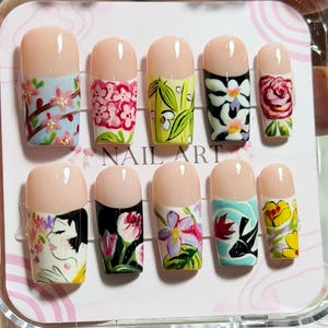 May include: A set of ten press-on nails in a clear plastic case, each featuring a unique hand-painted design including floral patterns, bamboo, a koi fish, and a stylized portrait. The nails have a nude base with colorful, detailed artwork.