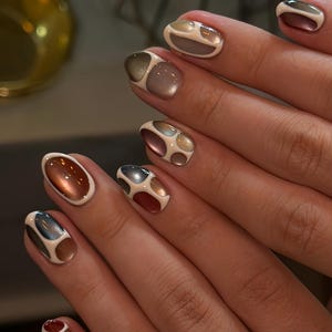 May include: Nails featuring a multi-colored design with a raised white border creating segmented shapes. The segments are filled with metallic and pearlescent shades of copper, bronze, silver, and slate blue, creating a textured, dimensional appearance.