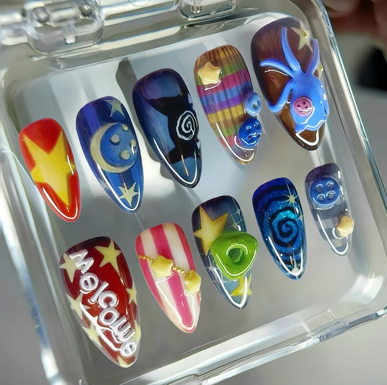 May include: A set of ten artificial nails with various designs. The nails feature a range of colors, including red, yellow, blue, and white, with designs such as stars, moons, swirls, and the word "Welcome".