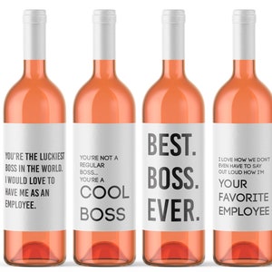 Może przedstawiać: Cztery butelki różowego wina z białymi etykietami i srebrnymi zamknięciami. Każda etykieta ma inny napis czarnym tekstem, w tym "Best Boss Ever" i "You're the Luckiest Boss in the World."