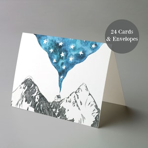 May include: A set of 24 greeting cards featuring a watercolor illustration of a small house nestled between two mountains with a blue starry sky above. The text "24 Cards & Envelopes" is printed in the top right corner.