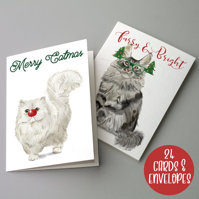 May include: Two Christmas cards with cat illustrations. One card says "Merry Catmas" and features a white cat with a red nose. The other card says "Furry & Bright" and shows a gray cat wearing glasses and a Christmas tree hat. A red circle says "24 Cards & Envelopes".