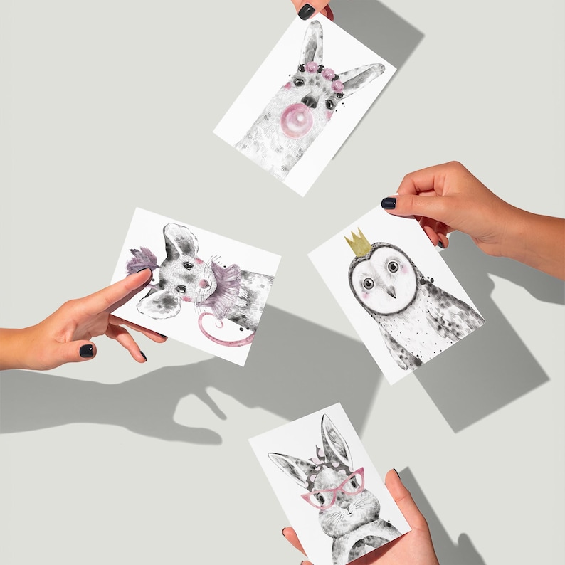 May include: Four animal art prints are held by hands. The prints feature a llama with a bubblegum bubble, a mouse with a frilly collar, an owl wearing a crown, and a rabbit with glasses. The illustrations are in black and white.