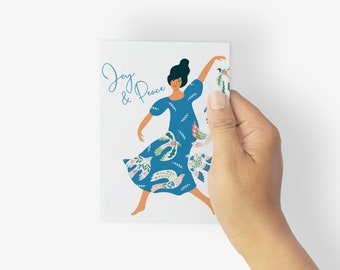 Op de afbeelding: Een rechthoekige wenskaart met een blauwe jurk met een wit vogel- en bloemenpatroon. De tekst Joy & Peace staat in blauw schrift aan de linkerkant gedrukt. Een figuur met donker haar is in een danshouding afgebeeld op de witte kaart.