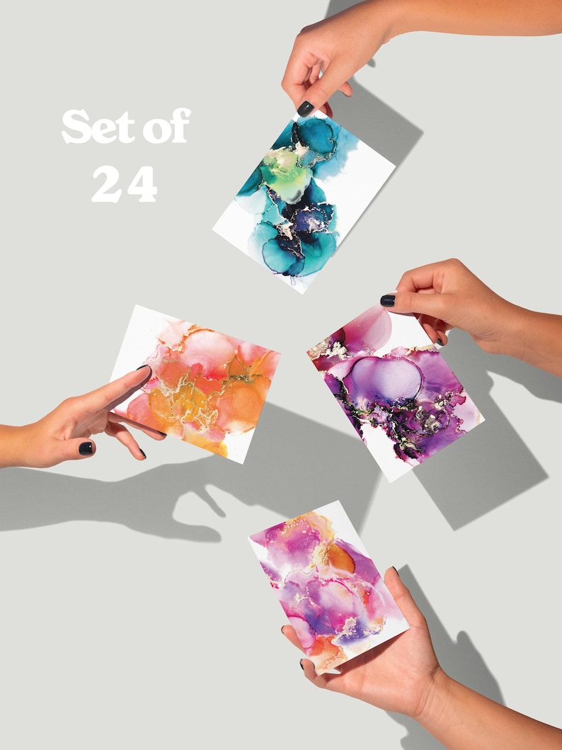 four hands holding up colorful abstract art cards against a light background.
