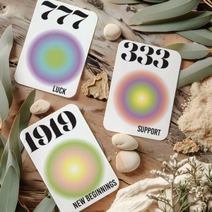 May include: Three cards with colorful gradient circles and numbers 777, 333, and 1919. The cards also have the words "Luck", "Support", and "New Beginnings" printed on them.