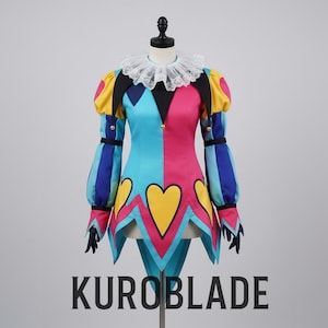 Könnte beinhalten: Ein farbenfrohes Narrenkostüm mit weißem Spitzenkragen, das ein geteiltes Design aus Blau und Rosa aufweist. Das Kostüm hat gelbe Herzmotive, Puffärmel und gestreifte blaue und lila Ärmel. Der Text "KUROBLADE" ist unten aufgedruckt.