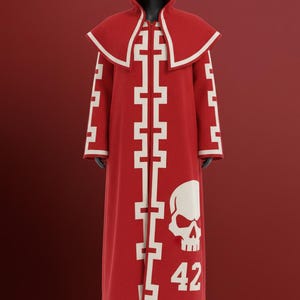 以下が含まれることがあります： 白いアクセントとスカルグラフィックが付いた赤いフード付きローブ。ローブは前面に白い十字のようなデザインと数字42が特徴です。「KUROLADE」という言葉が上部に印刷されています。