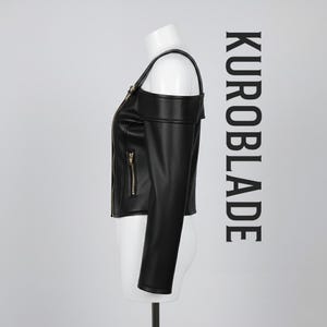 May include: Black leather jacket with a unique off-the-shoulder design. Features a gold zipper and the text "KUROBLADE" in black. The jacket is displayed on a mannequin.