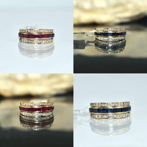 May include: Four gold rings with gemstones. Two rings feature red gemstones and diamonds, while the other two showcase blue gemstones and diamonds. The rings are stacked, reflecting on a shiny surface.