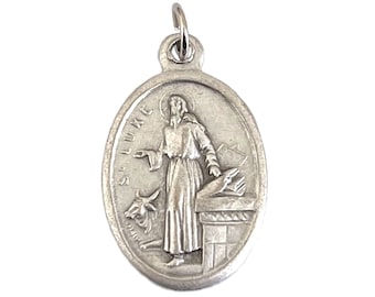 May include: Silver oval pendant featuring a depiction of Saint Luke, holding a scroll and a pen, with a bull at his feet. The pendant has the inscription "St Luke" on the left side.