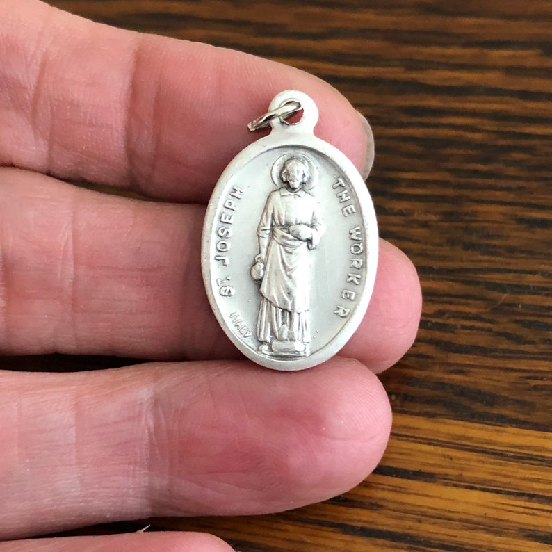 St Joseph the Worker Catholic Medals shown on fingers for different perspective