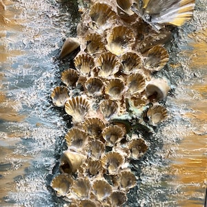 Puede incluir: Obra de arte texturizada con un grupo de conchas doradas y una estrella de mar sobre un fondo de pintura azul y dorada. Las conchas están dispuestas verticalmente, creando un tema costero.