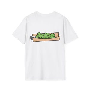 Könnte beinhalten: Weißes T-Shirt mit einer Cartoon-Grafik eines gerollten Gegenstands mit dem Wort "DOPE" in grünen Buchstaben. Der gerollte Gegenstand ist braun mit einem weißen Rand. Das T-Shirt ist aus einem weichen Material.