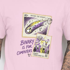 May include: A light pink v-neck t-shirt featuring two postage stamp-style graphics. The top graphic reads "Beyond the Binary" with a comet illustration. The bottom graphic reads "Binary is for Computers" with a gender symbol.