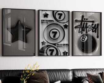 May include: Three framed wall art pieces. The first features a black star. The second has the number 7, stars, and the text "I'M SO LUCKY, LUCKY!". The third displays a black 8-ball and the Stussy logo. All are in black frames.