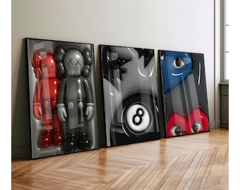 May include: Three framed art pieces featuring pop art designs. The first displays two red figures and a gray figure. The second shows a black and white eight ball. The third features a blue eye and red lips. All are in black frames.