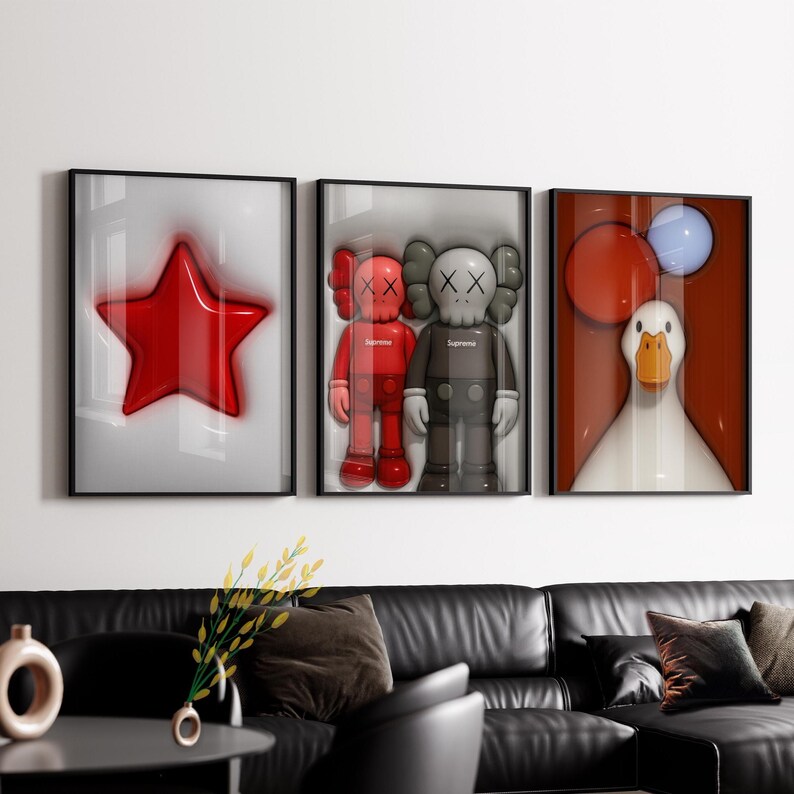 May include: Three framed art prints. The left print shows a glossy red star on a white background. The centre print features two KAWS figures. The right print depicts a white duck with red and blue balloons.