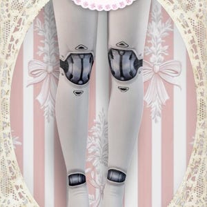 May include: A white ceramic mug with a black handle and the text "But First, Coffee" in a bold, black font. The mug is set against a blurred background, suggesting a cozy setting.