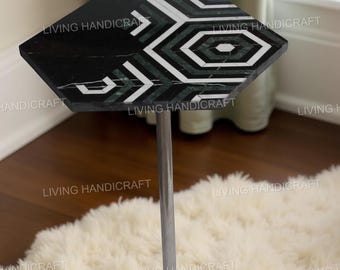 May include: A hexagonal side table with a black top inlaid with a geometric pattern of white and green marble. The table is supported by a chrome metal stem and a circular base. The words "LIVING HANDICRAFT" are printed on the table.
