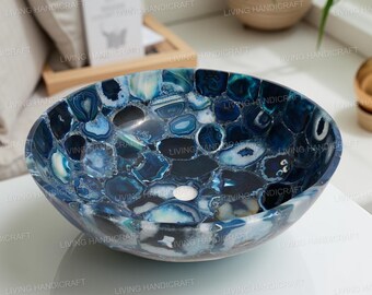 Pode incluir: Lavatório oval de pedra de ágata azul com acabamento polido. O lavatório apresenta um padrão de mosaico de peças de pedra azul, branca e preta. Um ralo branco é visível no centro. Um acessório de casa de banho único.