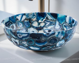 Pode incluir: Uma pia de pedra de ágata azul e branca em forma de tigela oval. A pia apresenta um padrão de mosaico de peças de pedra azul e branca. Uma torneira dourada é visível.