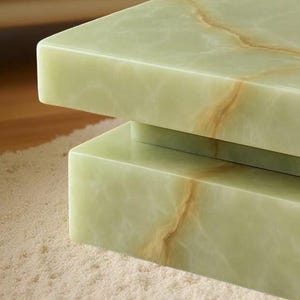 May include: Close-up of a two-tiered, rectangular table with a light green onyx surface. The onyx has natural brown veining, creating a unique pattern. The table is set on a light-colored, textured rug.