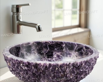 May include: A handcrafted, purple amethyst stone sink. The sink has a rough, textured exterior and a smooth interior. A chrome faucet is mounted on the wall behind the sink. The sink is a unique bathroom fixture.