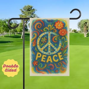 May include: A double-sided garden flag with a peace symbol design. The flag features a blue background with colorful swirls, flowers, and the word "PEACE" in yellow. The flag is displayed on a black metal stand.