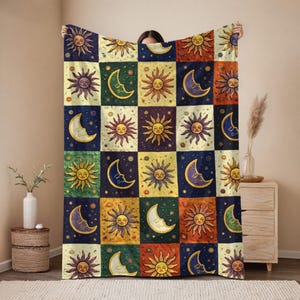 May include: A colorful throw blanket featuring a patchwork design with sun and moon motifs. The squares are in shades of blue, yellow, orange, and green. The blanket is made of a soft material and is perfect for adding a touch of bohemian style to any room.