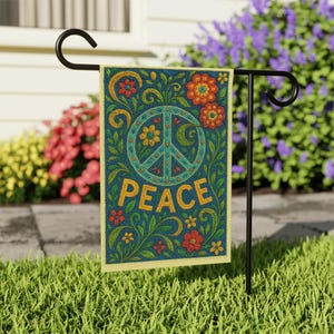 May include: A decorative garden flag featuring a peace symbol and the word "PEACE" in gold lettering. The flag has a dark blue background with floral and leaf designs in red, orange, and green. The flag is displayed on a black metal stand.