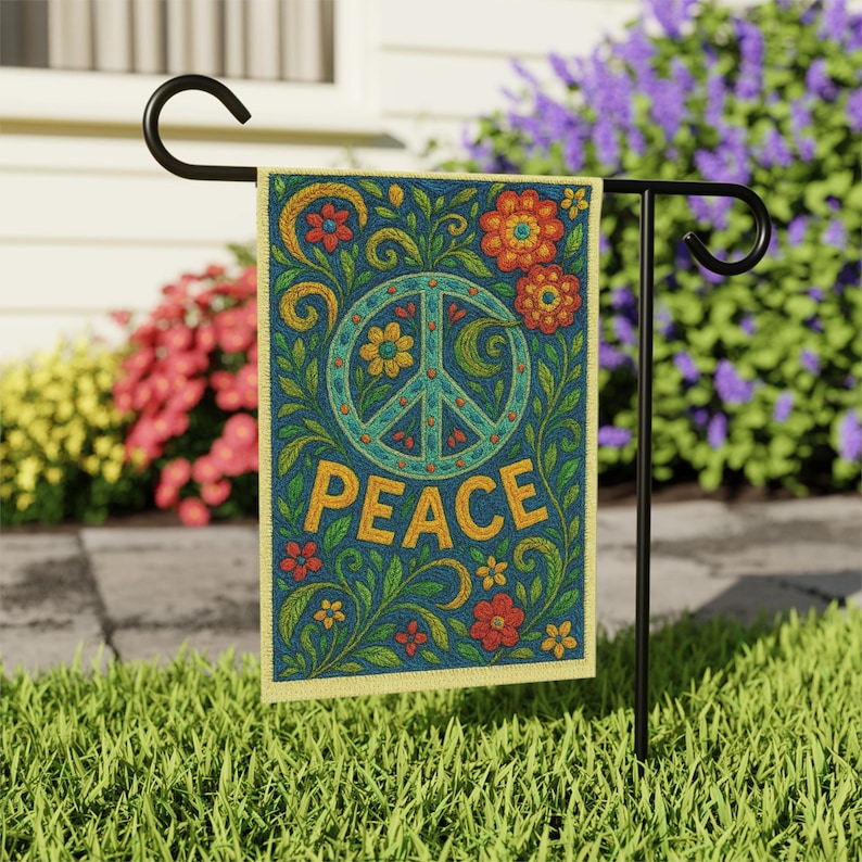May include: A decorative garden flag with a peace symbol and the word "PEACE" in gold lettering. The flag features a blue background with floral and leaf designs in red, orange, and green. The flag is displayed on a black metal stand.