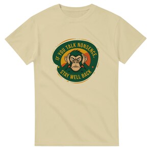 Könnte beinhalten: Beigefarbenes T-Shirt mit einem Cartoon-Affen, der sich die Ohren zuhält. Der Affe befindet sich in einem grünen und orangefarbenen Kreis mit dem Text "IF YOU TALK NONSENSE, STAY WELL BACK".