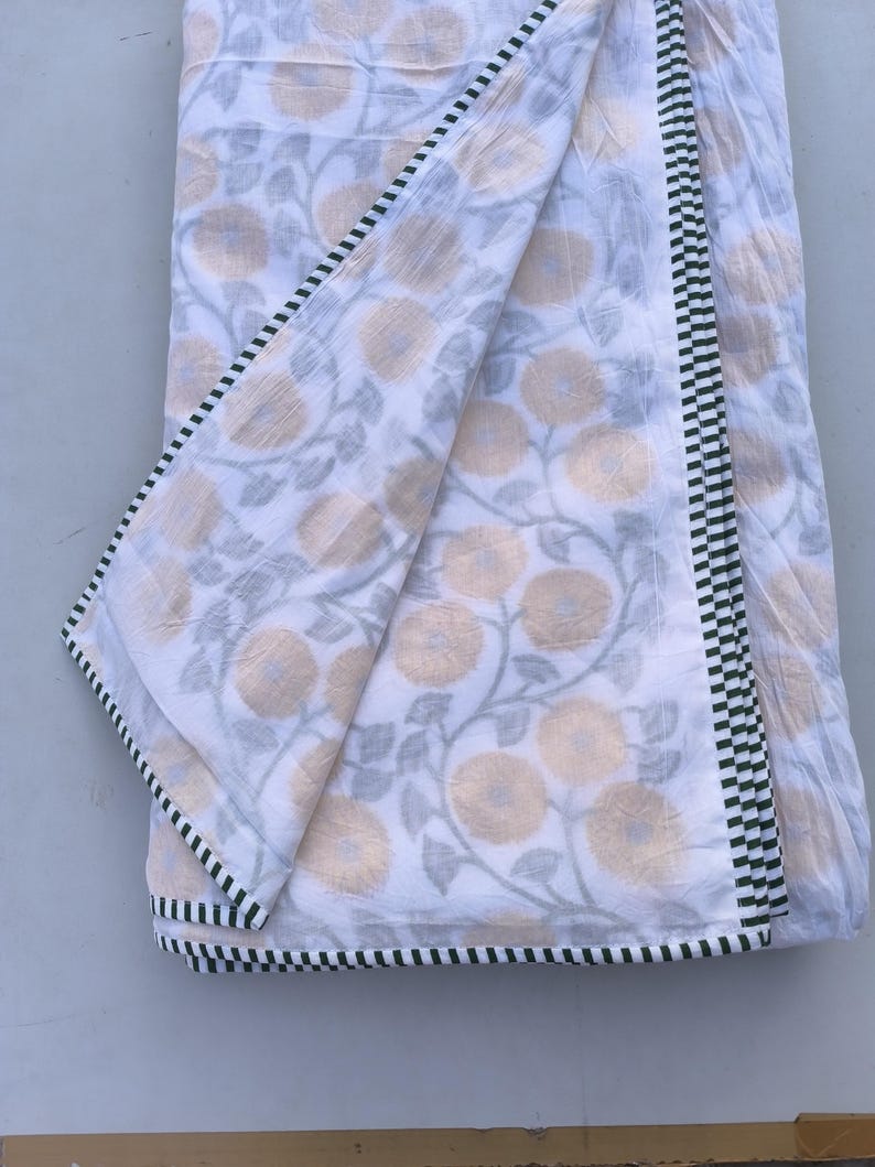 May include: White fabric with a floral pattern in shades of yellow and gray. The fabric has a black and white checkered border. The floral design features large, stylized flowers and winding vines, creating a soft, natural aesthetic.