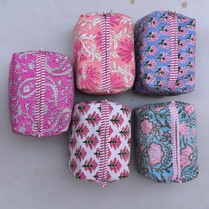 Puede incluir: Seis bolsas rectangulares de tela con estampados florales. Las bolsas presentan diseños florales rosas, azules y blancos sobre varios fondos. Cada bolsa tiene una franja vertical en el centro con una cremallera. Las bolsas son probablemente para almacenamiento o viajes.