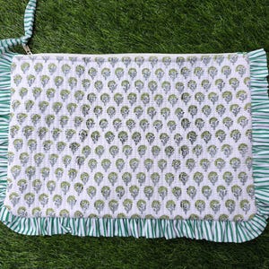 May include: A white clutch with a green floral pattern and a green and white striped ruffle trim. The clutch has a zipper closure and a green and white striped handle.