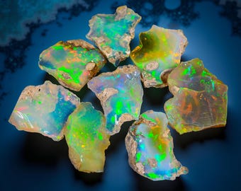 May include: A collection of raw opal gemstones, showcasing vibrant colors of green, blue, yellow, and orange. The opals have a rough, natural texture and are displayed against a dark blue background.
