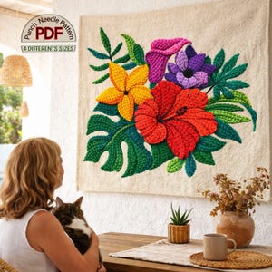 Puede incluir: Un tapiz floral hecho a mano con un diseño de aguja de perforación. Presenta un ramo de hibiscos rojos, flores amarillas, flores moradas y hojas verdes. La obra de arte se exhibe sobre una tela de tono neutro. El texto "Punch Needle PDF" y "4 DIFFERENT SIZES" es visible.