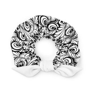 Puede incluir: Una diadema con estampado en blanco y negro con un diseño floral. La diadema está atada con dos extremos de tela blanca. El diseño es un patrón repetitivo de espirales y hojas.