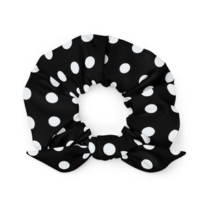Puede incluir: Coletero negro con lunares blancos. El accesorio para el cabello está hecho de una tela suave y presenta un detalle de lazo. Este coletero es una adición elegante a cualquier peinado.