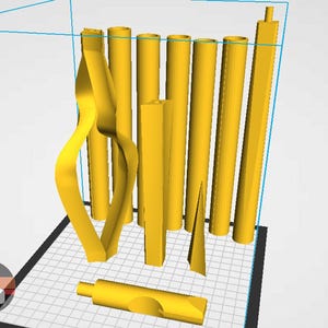 Puede incluir: Una colección de objetos amarillos impresos en 3D, que incluyen formas cilíndricas, rectangulares y curvas. Los objetos están dispuestos sobre una superficie similar a una cuadrícula, mostrando varios diseños y formas. La imagen es una representación del producto.