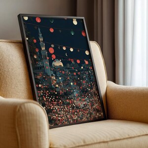 May include: A framed art print depicting a nighttime cityscape with a mosque and string lights. The artwork features a dark blue sky, illuminated buildings, and red and white circular lights. The print is displayed on a beige armchair.