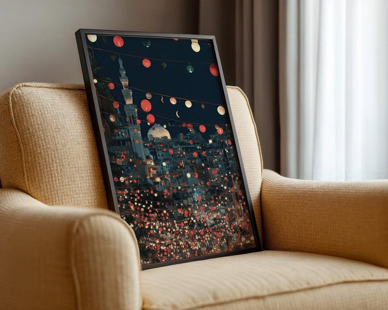 May include: A framed art print depicting a nighttime cityscape with a mosque and string lights. The artwork features a dark blue sky, illuminated buildings, and red and white circular lights. The print is displayed on a beige armchair.