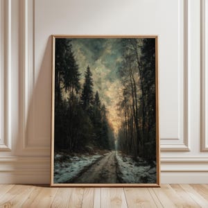 Op de afbeelding: Ingelijste kunstdruk van een boslandschap met een onverharde weg. Hoge bomen staan langs de weg, met sneeuw op de grond. De lucht is een mix van donkere en lichte kleuren. Het kunstwerk zit in een houten lijst.