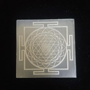 "Close-up of the intricate Shri Yantra engraving on a polished selenite crystal charger."