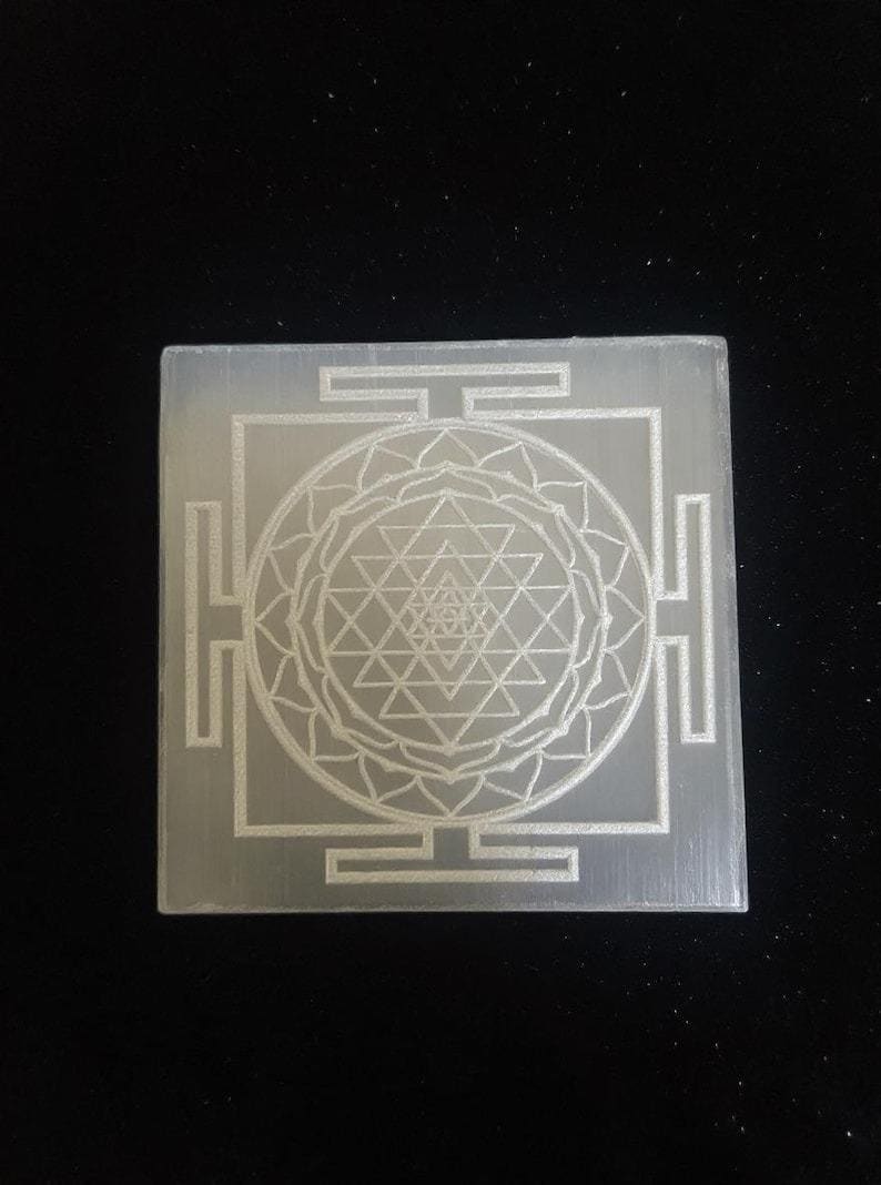 "Close-up of the intricate Shri Yantra engraving on a polished selenite crystal charger."